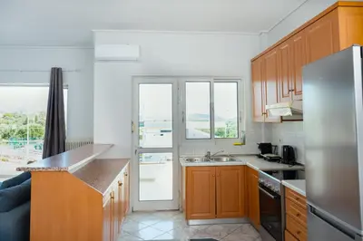 a kitchen with wooden cabinets and a stainless steel refrigerator at The Sunrise Apartment By Athens Airport 1 in Spáta