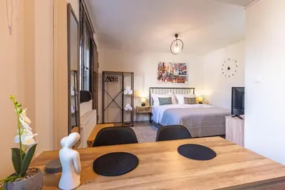 a room with a bed and a wooden table with a dining room at New, Comfy, Spotless Studio in Ilioupoli, Athens in Athens