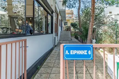 a blue sign on a fence in front of a building at New, Comfy, Spotless Studio in Ilioupoli, Athens in Athens
