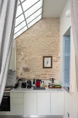 a kitchen with white cabinets and a brick wall at Athenian Cypress House, Atelier in Athens