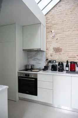 a kitchen with a black stove and white cabinets at Athenian Cypress House, Atelier in Athens