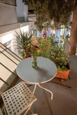a white table with a vase of flowers on a balcony at Athenian Cypress House, Studio in Athens