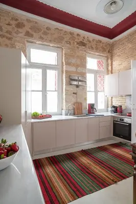 a kitchen with white cabinets and two windows and a rug at Athenian Cypress House, Maisonette in Athens