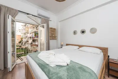 a bedroom with a white bed with a green blanket at Ble Elia Flat for two in Athens in Athens