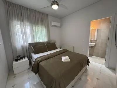 a bedroom with a large bed and a bathroom at Caza pool Glyfada in Athens
