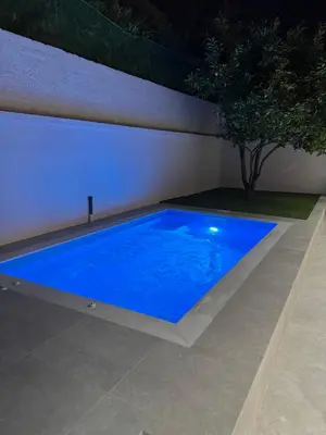 a large blue swimming pool in a backyard at night at Caza pool Glyfada in Athens