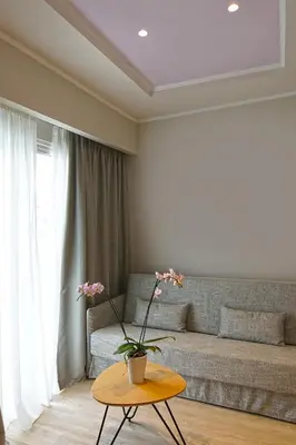 a living room with a couch and a table with flowers on it at Athens Cypria Hotel in Athens