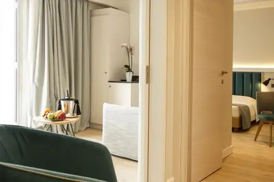 a room with a green couch and a bedroom at Athens Cypria Hotel in Athens