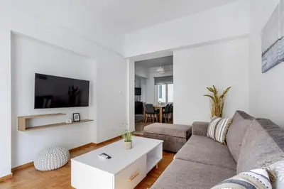 a living room with a couch and a tv on a wall at Arco - Sleek 2-BR Apt in the Heart of Athens in Athens