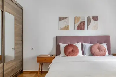 a bedroom with a bed with pink pillows at Arco - Sleek 2-BR Apt in the Heart of Athens in Athens