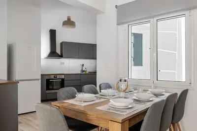 a kitchen with a wooden table with chairs around it at Arco - Sleek 2-BR Apt in the Heart of Athens in Athens