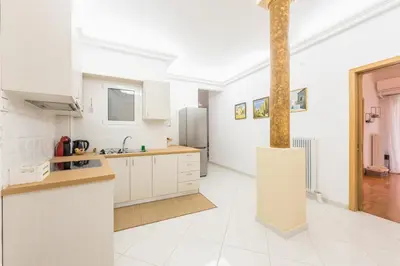 a kitchen with white cabinets and a pole at Ble Elia Acropolis 2bdr Suite in Athens