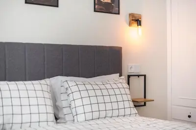 a bed with a gray headboard and white pillows at Platon At Philopappou By Greece Apartments in Athens