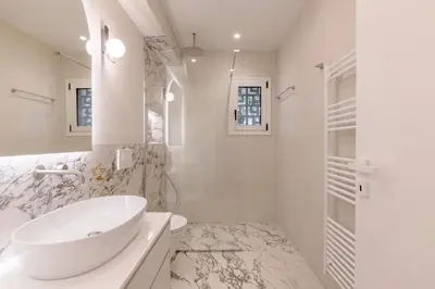 a white bathroom with a sink and a shower at Minimal Luxury Apartments in Kolonaki by UPSTREET in Athens