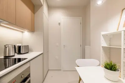 a kitchen with white counters and a table and a chair at Minimal Luxury Apartments in Kolonaki by UPSTREET in Athens