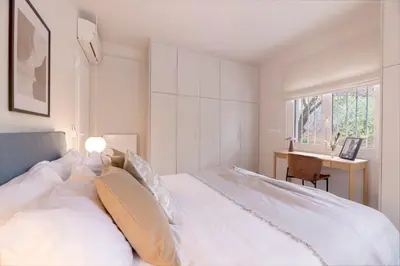 a bedroom with a white bed with a desk and a window at Minimal Luxury Apartments in Kolonaki by UPSTREET in Athens