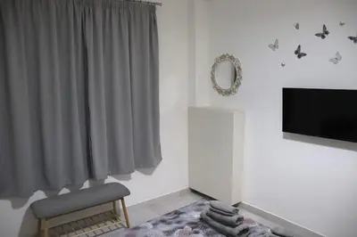a living room with a television and a chair at Cozy Mirror Apartment in Athens