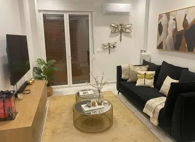 a living room with a black couch and a table at Amazing Apt with 2 Bedrooms in Pagkrati in Athens