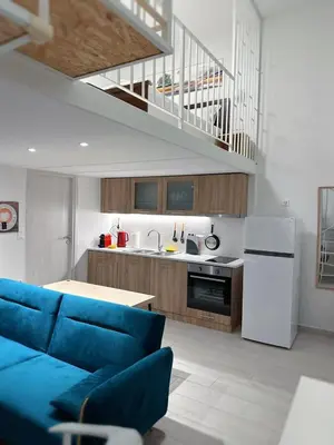 a living room with a blue couch and a kitchen at Glyfada Sea Breeze Loft A in Athens