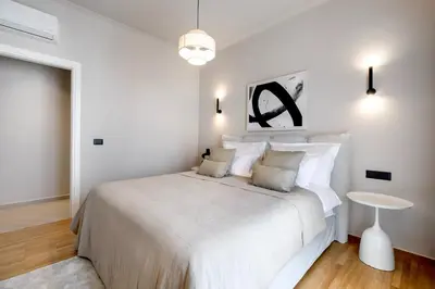 a white bedroom with a large bed and a table at Syntagma Acropolis View Residence in Athens