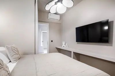 a white room with a bed and a tv on a wall at Syntagma Acropolis View Residence in Athens