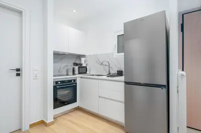 a kitchen with white cabinets and a refrigerator at Coastal Charm Elegant 1BR at Marina Zea Piraeus in Piraeus