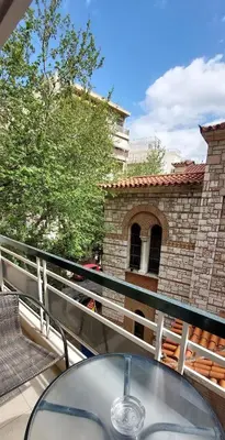 a glass table on a balcony with a brick building at Lovely apartment in Acropolis museum in Athens