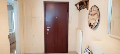 a brown door in a hallway with a clock on the wall at Lovely apartment in Acropolis museum in Athens
