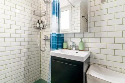 a white tiled bathroom with a sink and a mirror at Cosy Apartment in the Heart of Athens in Athens