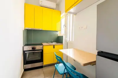 a kitchen with yellow cabinets and a table and chairs at Cosy Apartment in the Heart of Athens in Athens