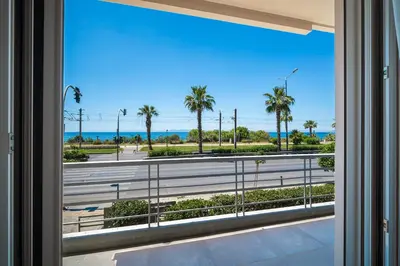 a window with a view of a road and palm trees at The Seafront Niche in Athens