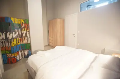 a bedroom with a white bed and a wooden cabinet at Cozy Apartment Downtown Athens III in Athens