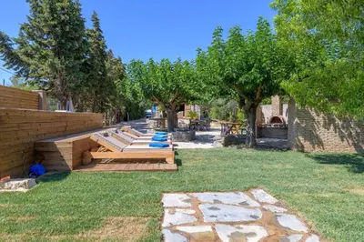 a row of benches in a yard with trees at Petrino pool house in Athens