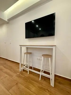 a white table with two stools and a tv on a wall at Pagrati Cozy Lux Studio-Chremonidou street in Athens