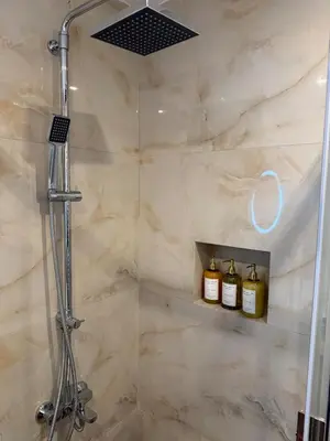 a bathroom with a shower with two bottles of oils at Pagrati Cozy Lux Studio-Chremonidou street in Athens