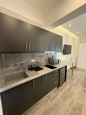 a kitchen with black cabinets and a counter top at Pagrati Luxury Gray Studio-Chremonidou street in Athens
