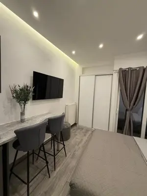 a living room with a table and chairs and a television at Pagrati Luxury Gray Studio-Chremonidou street in Athens