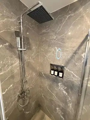a bathroom with a shower with three bottles of soap at Pagrati Luxury Gray Studio-Chremonidou street in Athens