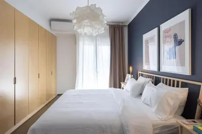 a bedroom with a large white bed with a chandelier at Amazing flat just 500 m from Acropolis museum in Athens