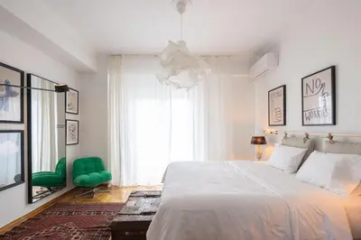 a bedroom with a white bed and a green chair at Amazing flat just 500 m from Acropolis museum in Athens