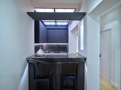 a kitchen with a black counter with two chairs at Adorac in Athens