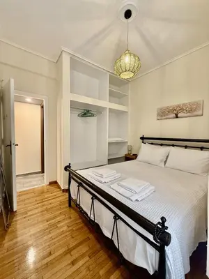 a bedroom with a bed with white sheets and a chandelier at Near Acropolis-Athens in Athens