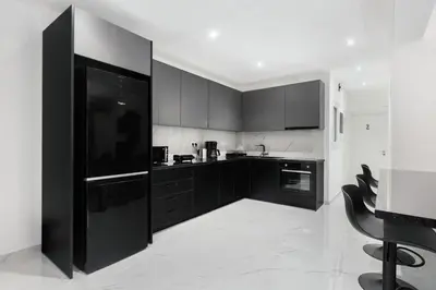 a black and white kitchen with black cabinets at Flouris Apartments in Athens