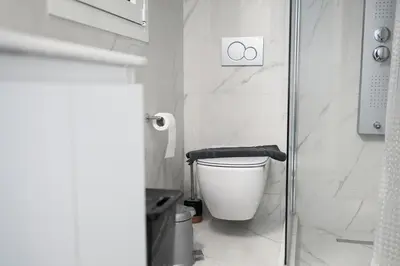a white bathroom with a toilet and a shower at Flouris Apartments in Athens
