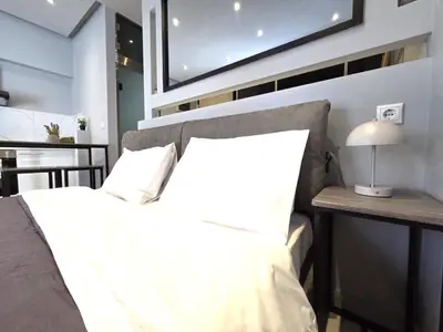 a bedroom with a white bed and a table with a lamp at Georgette's Charming Studio near Metro by MPS in Athens
