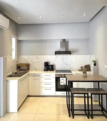 a kitchen with white cabinets and a table with chairs at Georgette's Charming Studio near Metro by MPS in Athens