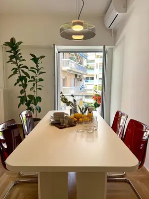 a dining room table with chairs and a large window at Quaint & Central Acropolis apartment in Athens