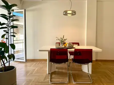 a kitchen with a white table and red chairs at Quaint & Central Acropolis apartment in Athens