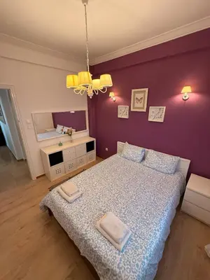 a bedroom with a bed and a purple wall at Delightful Seaside & Romantic in Athens