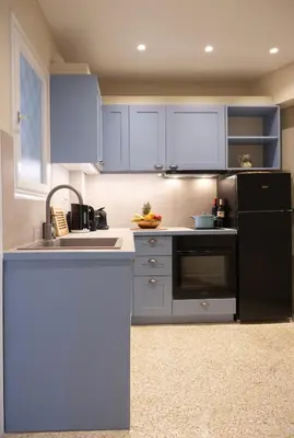 a kitchen with blue cabinets and a black refrigerator at Acropolis Luxe Stay in Athens